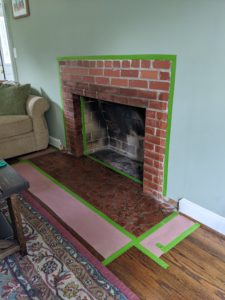 Brick fireplace prepped with paper and painter's tape to limewash